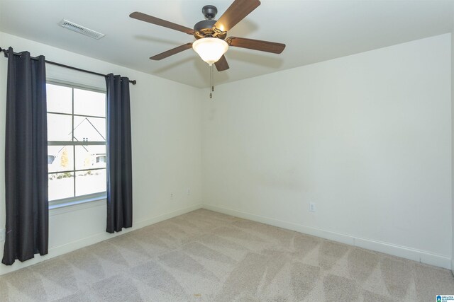 carpeted spare room featuring ceiling fan and a wealth of natural light