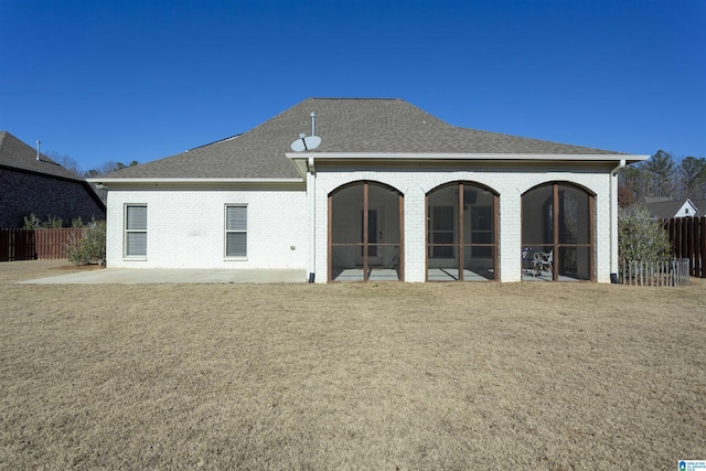 back of property with a sunroom and a lawn