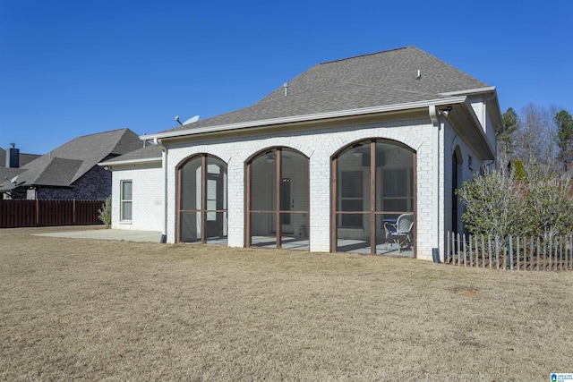 back of property featuring a lawn, a patio area, and a sunroom