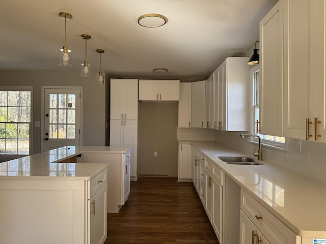 kitchen with sink, white cabinetry, tasteful backsplash, a kitchen island, and pendant lighting