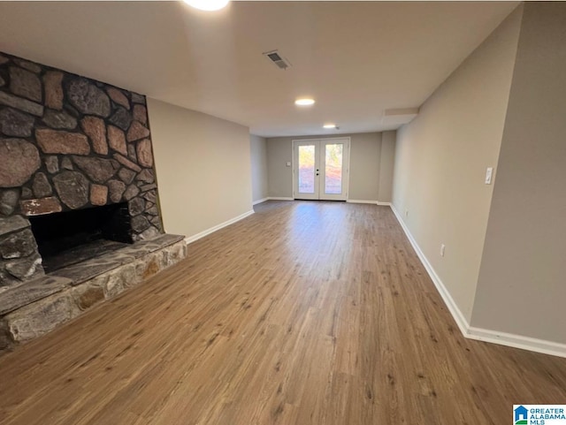 unfurnished living room featuring french doors, a fireplace, and hardwood / wood-style flooring