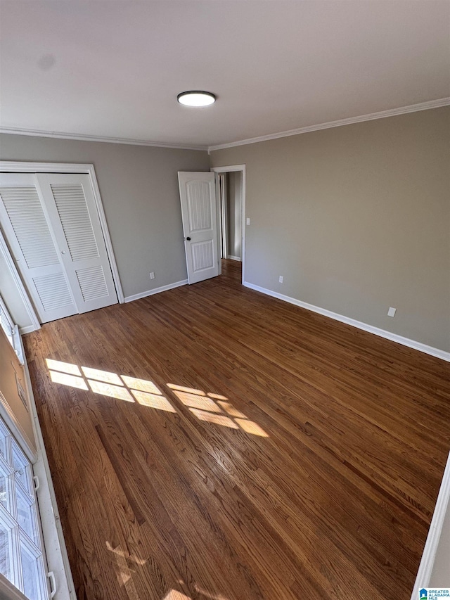 unfurnished bedroom with ornamental molding, a closet, and dark hardwood / wood-style flooring