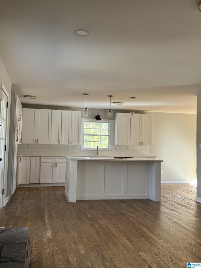 kitchen with sink, white cabinetry, backsplash, pendant lighting, and dark wood-type flooring