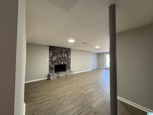 unfurnished living room featuring hardwood / wood-style floors and a stone fireplace