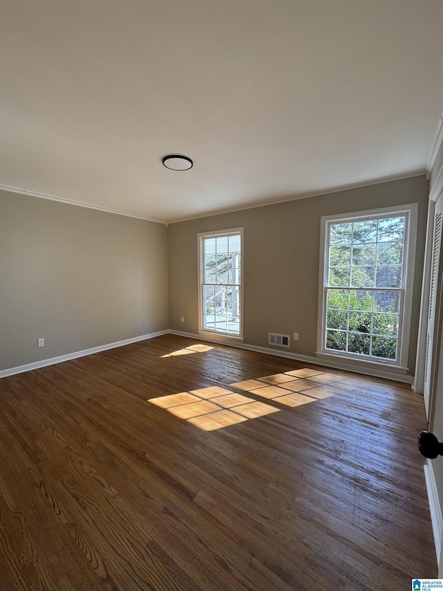 empty room with ornamental molding and dark wood-type flooring