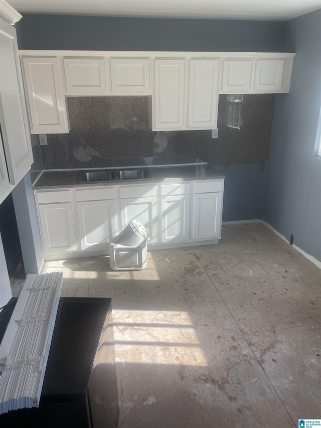 kitchen featuring white cabinets, backsplash, and sink