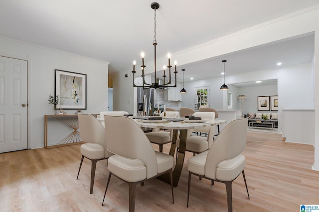 dining room featuring ornamental molding, light hardwood / wood-style floors, and an inviting chandelier