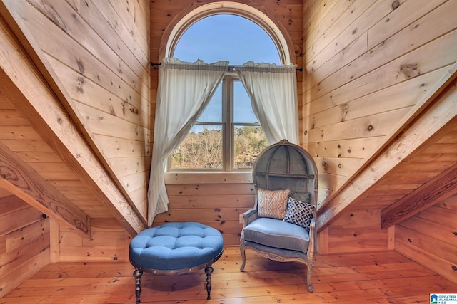 sitting room with beamed ceiling, wood-type flooring, wooden walls, and wood ceiling