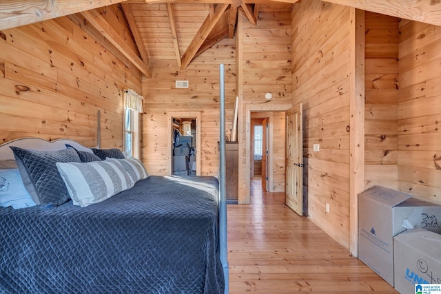 unfurnished bedroom with beam ceiling, light hardwood / wood-style flooring, high vaulted ceiling, wooden walls, and wood ceiling