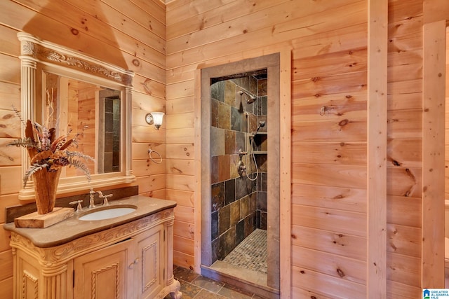 bathroom featuring a tile shower, wooden walls, and vanity