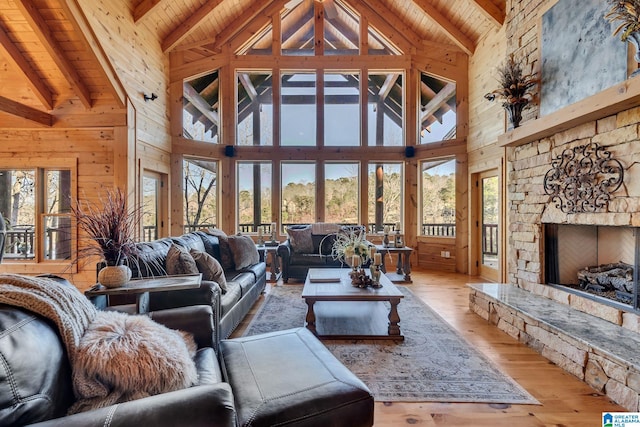 living room featuring beam ceiling, high vaulted ceiling, light hardwood / wood-style floors, a fireplace, and wood ceiling