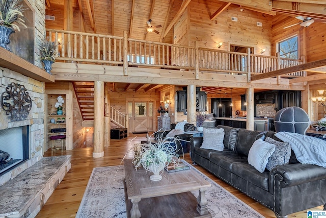 living room featuring beam ceiling, high vaulted ceiling, wooden ceiling, light hardwood / wood-style floors, and wood walls