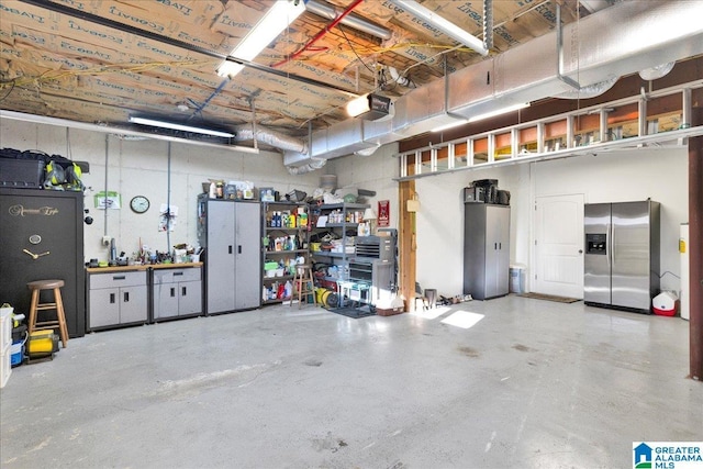 garage with stainless steel refrigerator with ice dispenser, a workshop area, and a garage door opener