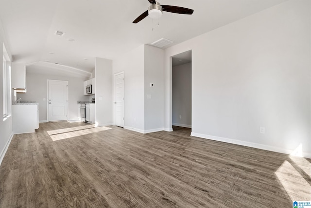 unfurnished living room featuring lofted ceiling, baseboards, visible vents, ceiling fan, and wood finished floors