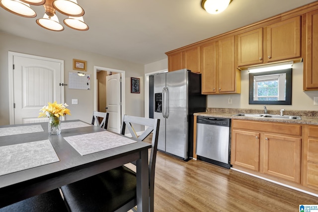 kitchen with light wood-type flooring, sink, appliances with stainless steel finishes, and an inviting chandelier