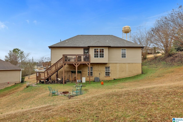 back of property featuring central air condition unit, a wooden deck, a yard, and an outdoor fire pit