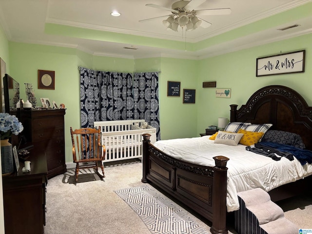 carpeted bedroom featuring ceiling fan, crown molding, and a tray ceiling