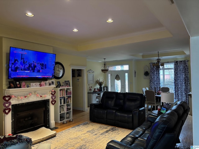 living room featuring hardwood / wood-style floors, ornamental molding, and a raised ceiling