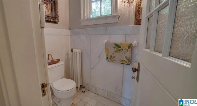 bathroom featuring tile patterned floors, toilet, tile walls, and radiator