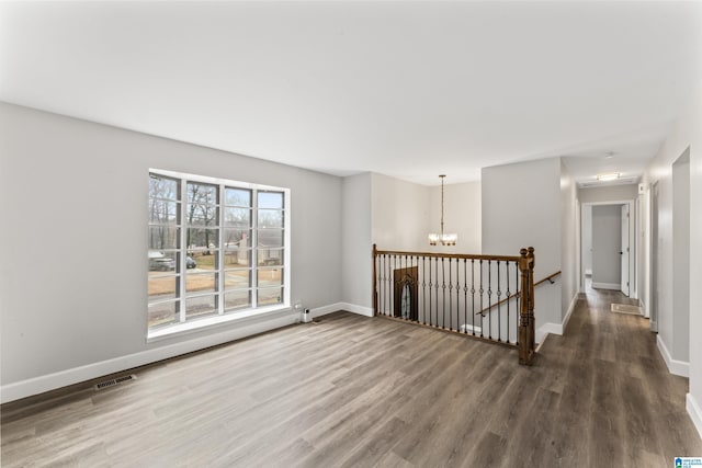 spare room featuring dark wood-type flooring and a notable chandelier