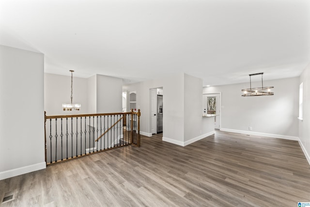 unfurnished room featuring wood-type flooring and a notable chandelier