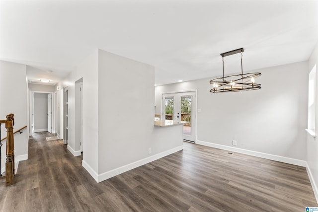 unfurnished dining area with french doors, dark wood-type flooring, and an inviting chandelier