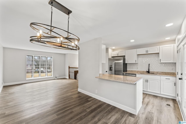 kitchen featuring sink, hanging light fixtures, stainless steel appliances, decorative backsplash, and white cabinets