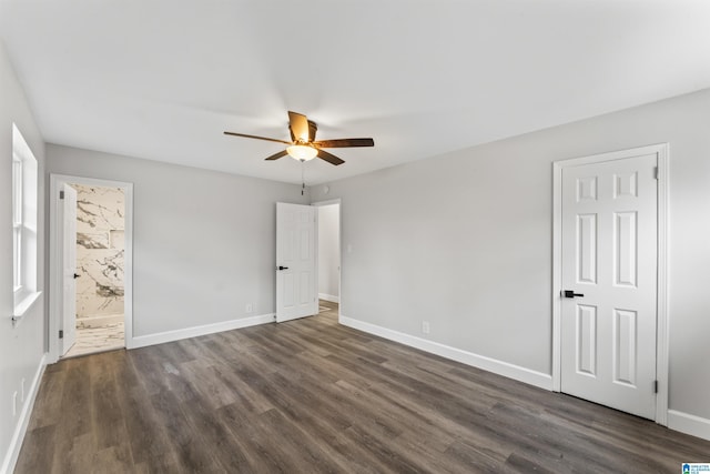 unfurnished bedroom featuring ensuite bath, ceiling fan, and dark wood-type flooring