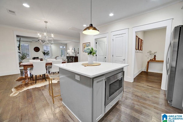 kitchen featuring pendant lighting, a center island, dark hardwood / wood-style flooring, and appliances with stainless steel finishes