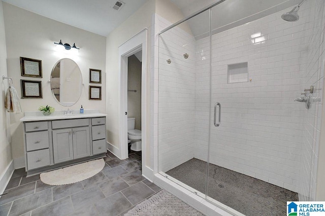 bathroom with tile patterned flooring, vanity, a shower with shower door, and toilet