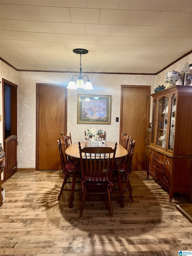 dining room with light wood-type flooring, an inviting chandelier, and crown molding