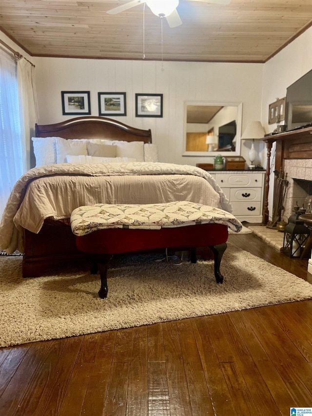 bedroom with a stone fireplace, ceiling fan, wood ceiling, and hardwood / wood-style flooring