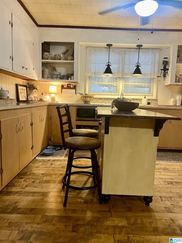 bar featuring hardwood / wood-style floors, decorative light fixtures, and light brown cabinetry