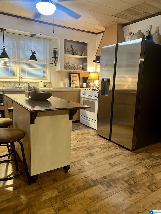 kitchen with a breakfast bar, decorative light fixtures, a kitchen island, stainless steel fridge with ice dispenser, and white range with gas cooktop