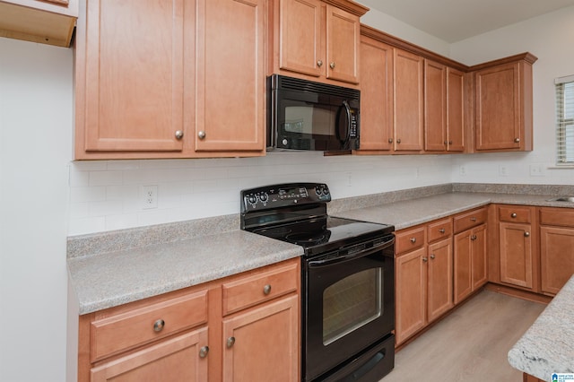 kitchen with light hardwood / wood-style floors and black appliances