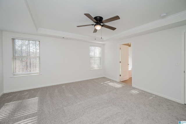 carpeted spare room with plenty of natural light, ceiling fan, and a raised ceiling