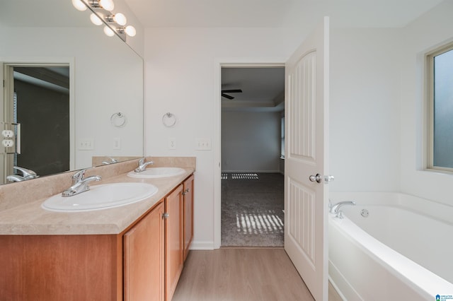 bathroom with a bathing tub, ceiling fan, wood-type flooring, and vanity