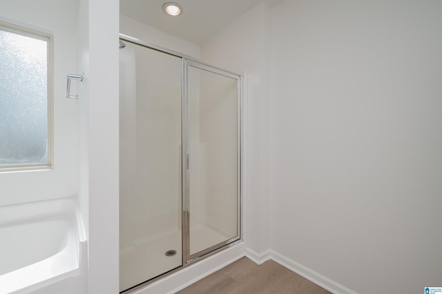 bathroom with hardwood / wood-style flooring, a healthy amount of sunlight, and walk in shower