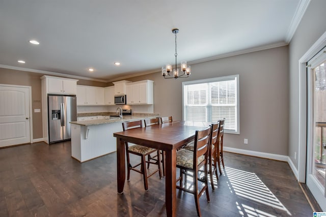 dining space featuring dark hardwood / wood-style floors, an inviting chandelier, ornamental molding, and sink