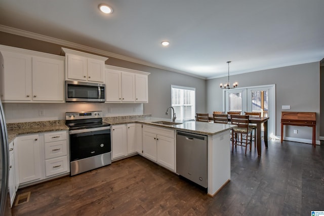 kitchen featuring kitchen peninsula, stainless steel appliances, sink, decorative light fixtures, and white cabinets