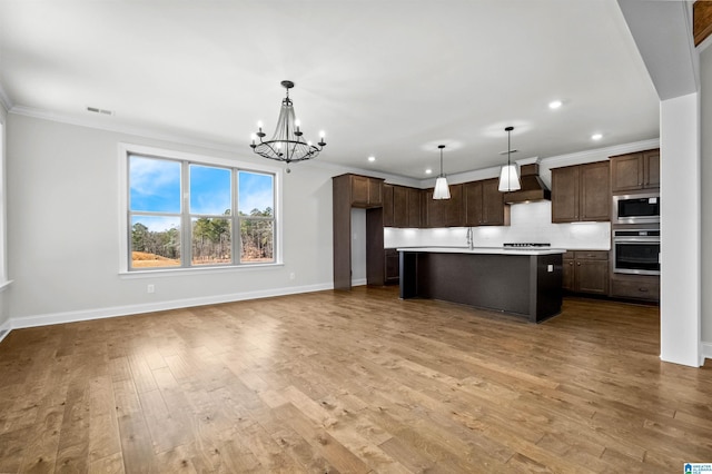 kitchen featuring decorative light fixtures, stainless steel appliances, custom range hood, and a kitchen island