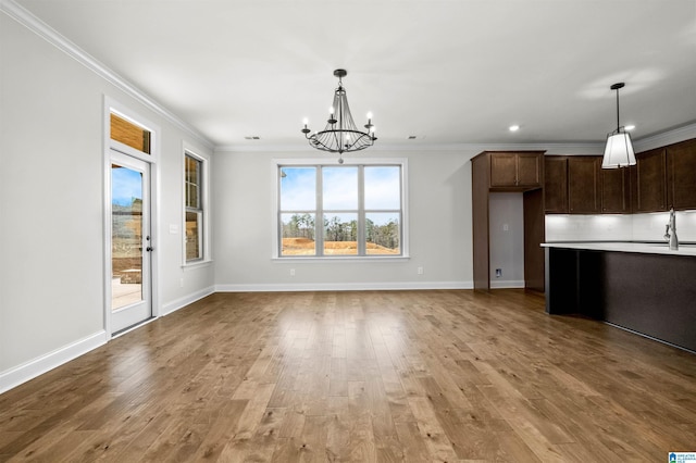 interior space with tasteful backsplash, hanging light fixtures, crown molding, and light hardwood / wood-style floors