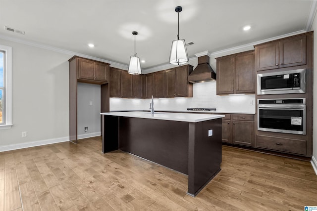 kitchen with sink, custom range hood, built in microwave, decorative light fixtures, and oven