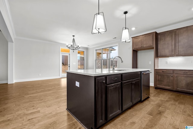 kitchen featuring sink, a kitchen island with sink, ornamental molding, light hardwood / wood-style floors, and decorative light fixtures