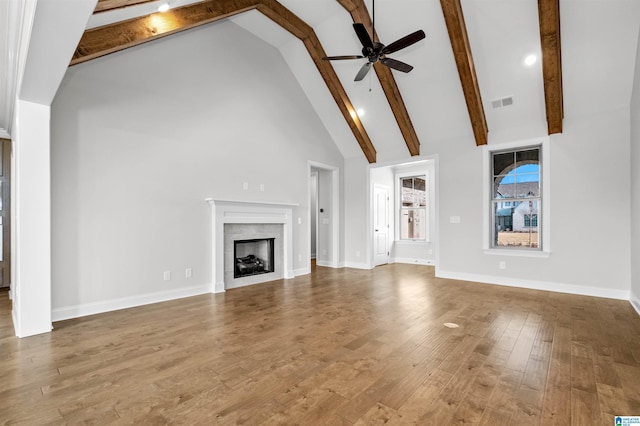 unfurnished living room with hardwood / wood-style flooring, ceiling fan, high vaulted ceiling, and beamed ceiling