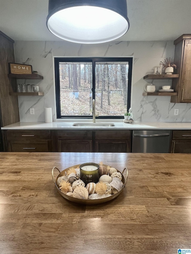 kitchen with backsplash, sink, stainless steel dishwasher, and dark brown cabinets