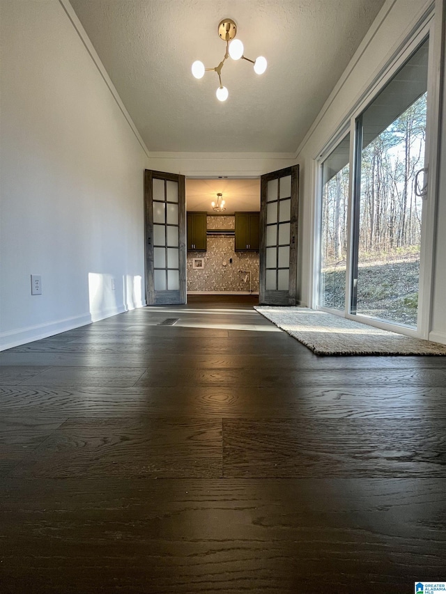 unfurnished living room with french doors, dark wood-type flooring, lofted ceiling, and an inviting chandelier