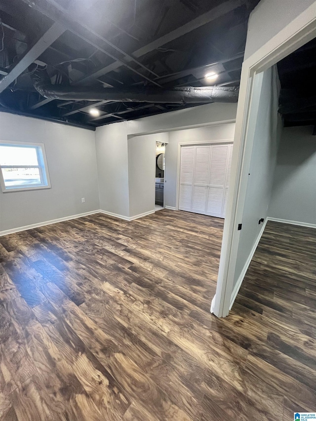 basement with stacked washer and clothes dryer and dark hardwood / wood-style floors