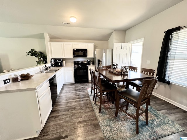 kitchen featuring sink, white cabinetry, dark wood-type flooring, and black appliances