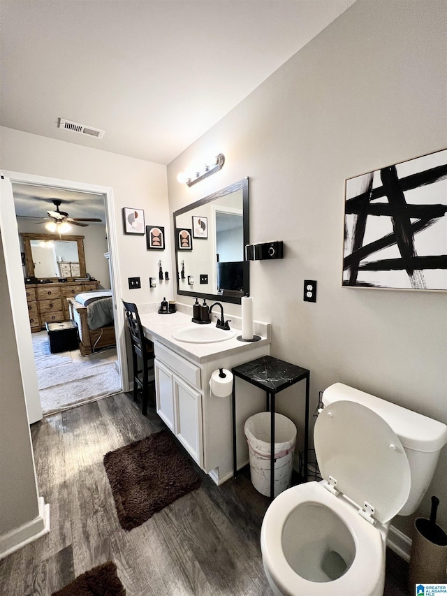 bathroom with hardwood / wood-style floors, vanity, toilet, and ceiling fan